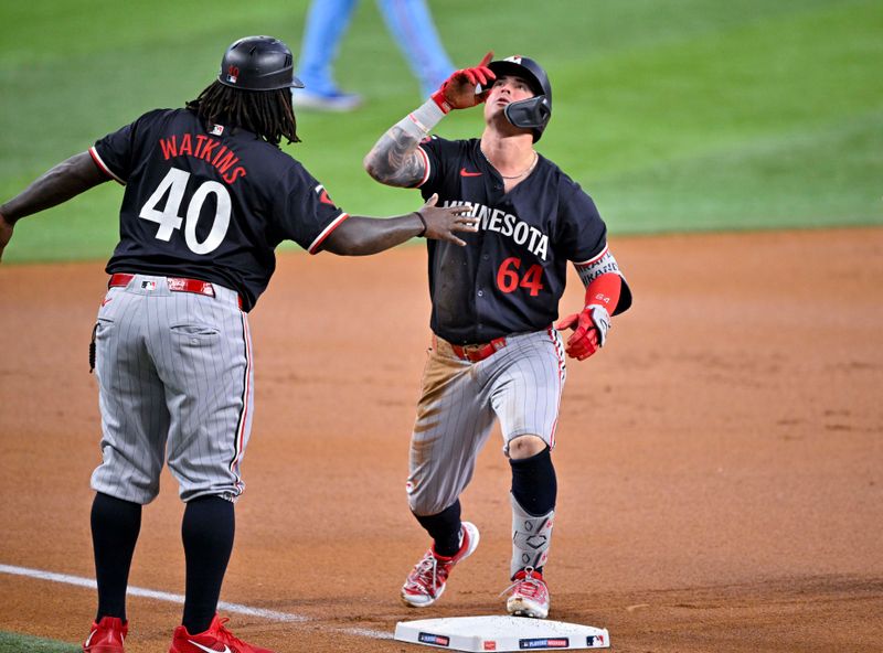 Aug 18, 2024; Arlington, Texas, USA; Minnesota Twins third base coach/outfield coach Tommy Watkins (40) and third baseman Jose Miranda (64) celebrate at third base during the first inning against the Texas Rangers at Globe Life Field. Mandatory Credit: Jerome Miron-USA TODAY Sports