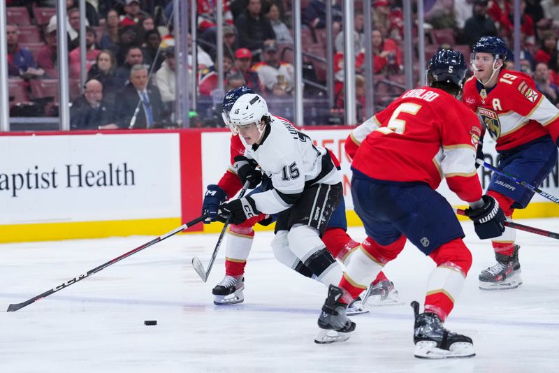 Jan 29, 2025; Sunrise, Florida, USA; Los Angeles Kings center Alex Turcotte (15) skates with the puck against Florida Panthers defenseman Aaron Ekblad (5) during the first period at Amerant Bank Arena. Mandatory Credit: Rich Storry-Imagn Images