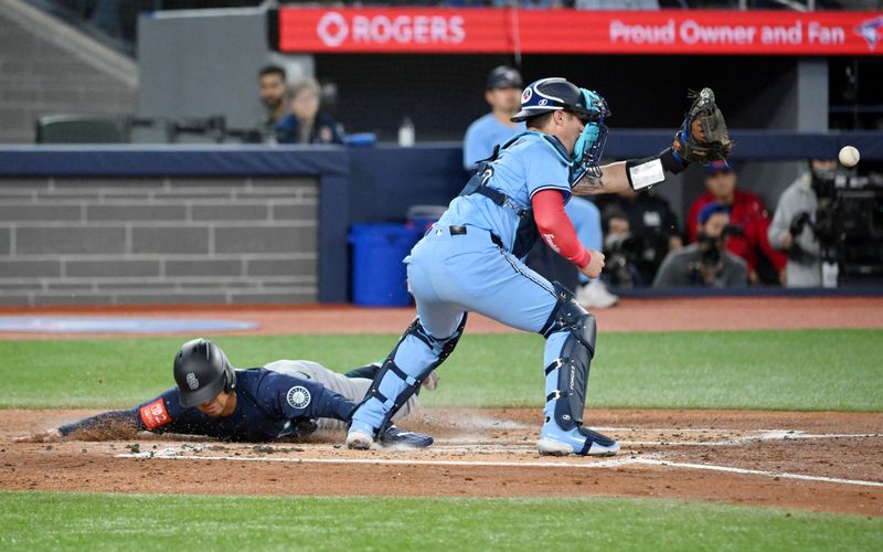 Apr 20, 2025; Toronto, Ontario, CAN;  Seattle Mariners center fielder Julio Rodriguez (44) scores a run as Toronto Blue Jays catcher Tyler Heineman (55) waits for the throw in the second inning at Rogers Centre. Mandatory Credit: Dan Hamilton-Imagn Images