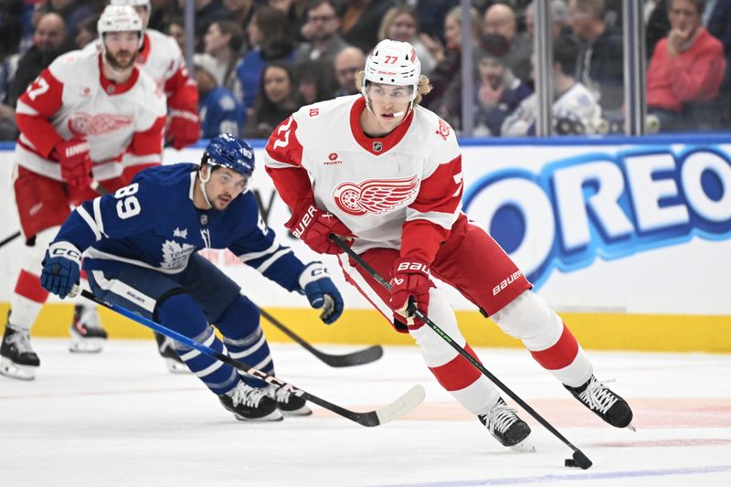 Jan 21, 2026; Toronto, Ontario, CAN;  Detroit Red Wings defenseman Simon Edvinsson (77) skates the puck away from Toronto Maple Leafs forward Nick Robertson (89) in the first period at Scotiabank Arena. Mandatory Credit: Dan Hamilton-Imagn Images