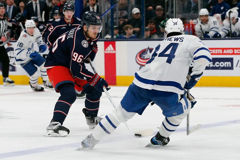 Dec 29, 2023; Columbus, Ohio, USA; Columbus Blue Jackets center Jack Roslovic (96) carries the puck as Toronto Maple Leafs center Auston Matthews (34) defends during the third period at Nationwide Arena. Mandatory Credit: Russell LaBounty-USA TODAY Sports