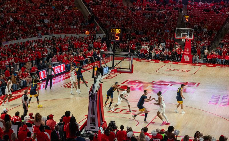 Jan 6, 2024; Houston, Texas, USA Houston Cougars guard Ryan Elvin (20) makes a three point basket against West Virginia Mountaineers forward Akok Akok (13) in the first half  at Fertitta Center. Mandatory Credit: Thomas Shea-USA TODAY Sports