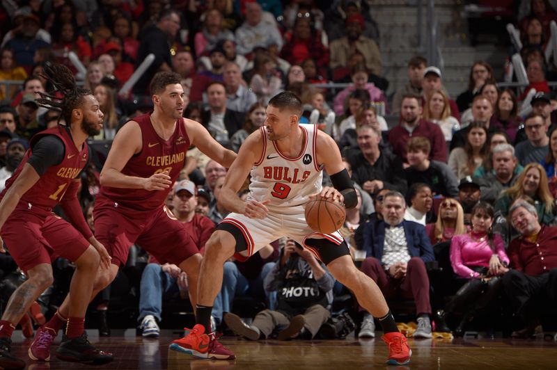 CLEVELAND, OH - FEBRUARY 14: Nikola Vucevic #9 of the Chicago Bulls handles the ball against Georges Niang #20 and Darius Garland #10 of the Cleveland Cavaliers during the game on February 14, 2024 at Rocket Mortgage FieldHouse in Cleveland, Ohio. NOTE TO USER: User expressly acknowledges and agrees that, by downloading and/or using this Photograph, user is consenting to the terms and conditions of the Getty Images License Agreement. Mandatory Copyright Notice: Copyright 2024 NBAE (Photo by David Liam Kyle/NBAE via Getty Images)