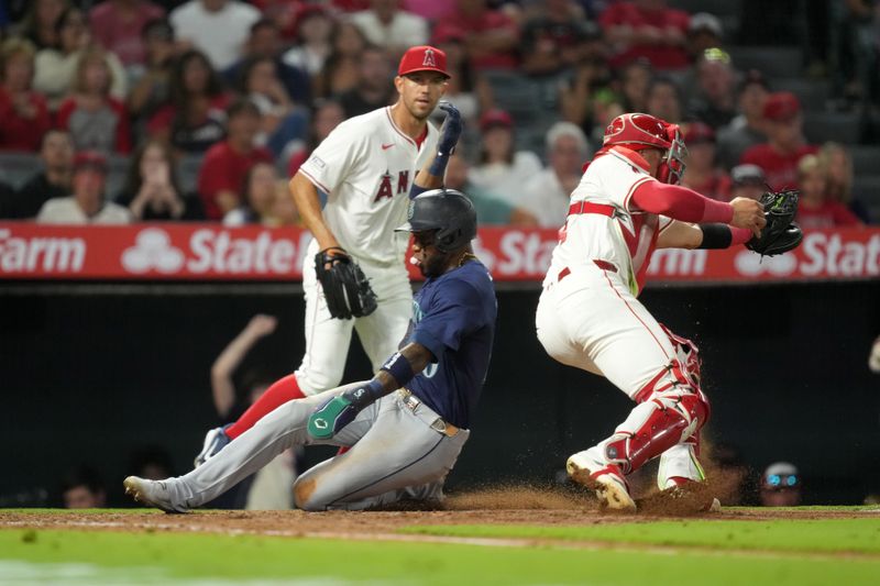 Aug 31, 2024; Anaheim, California, USA; Seattle Mariners center fielder Victor Robles (10) slides into home plate to beat a throw to Los Angeles Angels catcher Logan O'Hoppe (14) to score in the fourth inning at Angel Stadium. Mandatory Credit: Kirby Lee-USA TODAY Sports