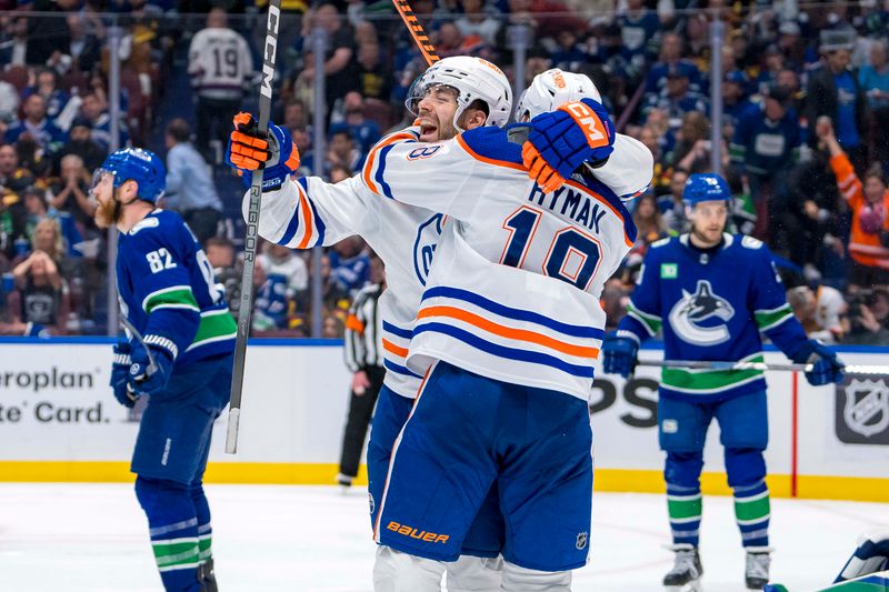 May 10, 2024; Vancouver, British Columbia, CAN; Edmonton Oilers defenseman Evan Bouchard (2) and forward Zach Hyman (18) celebrate Bouchard’s game winning goal against the Vancouver Canucks during the first overtime in game two of the second round of the 2024 Stanley Cup Playoffs at Rogers Arena. Mandatory Credit: Bob Frid-USA TODAY Sports