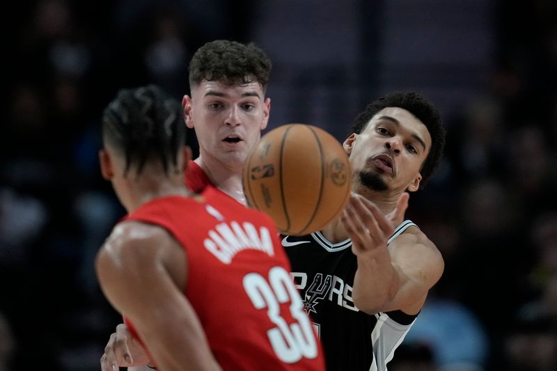 PORTLAND, OREGON - DECEMBER 13: Toumani Camara #33 of the Portland Trail Blazers (L) attempts to steal the ball away from Victor Wembanyama #1 of the San Antonio Spurs as Donovan Clingan #23 of the Portland Trail Blazers looks on during the first half at Moda Center on December 13, 2024 in Portland, Oregon. NOTE TO USER: User expressly acknowledges and agrees that, by downloading and or using this photograph, User is consenting to the terms and conditions of the Getty Images License Agreement. (Photo by Soobum Im/Getty Images)