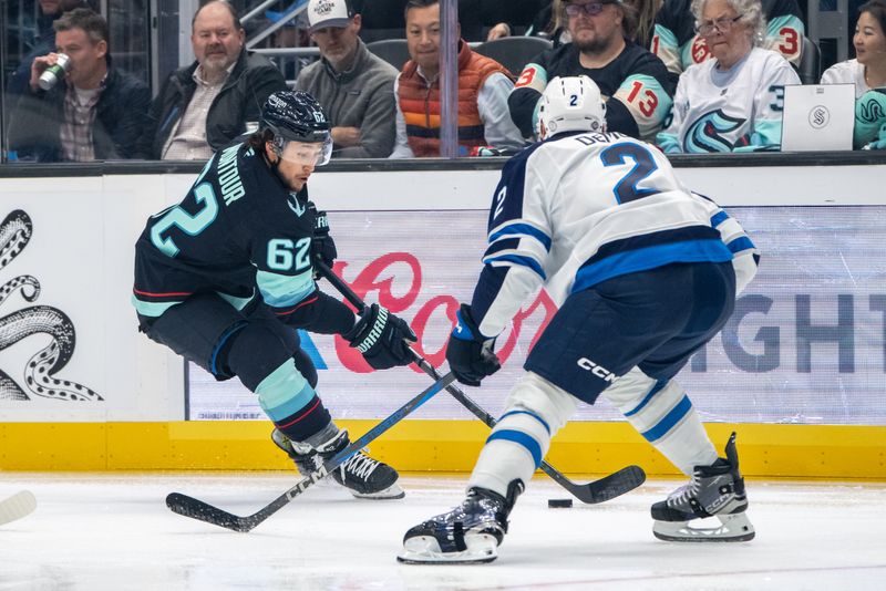 Oct 24, 2024; Seattle, Washington, USA;  Seattle Krakendefenseman Brandon Montour (62) skates against Winnipeg Jets defenseman Dylan DeMelo (2) during the second period at Climate Pledge Arena. Mandatory Credit: Stephen Brashear-Imagn Images