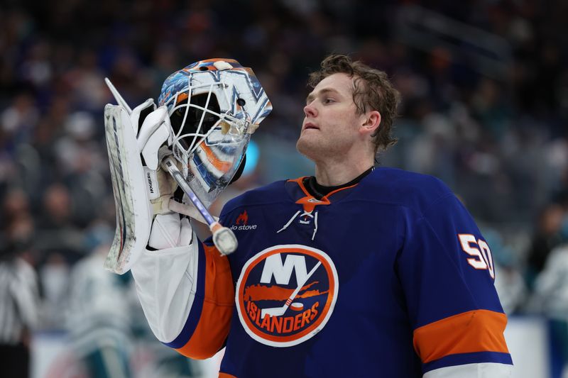 Jan 18, 2025; Elmont, New York, USA;  New York Islanders goaltender Marcus Hogberg (50) adjust his mask during a break in the action against the San Jose Sharks during the first period at UBS Arena. Mandatory Credit: Thomas Salus-Imagn Images