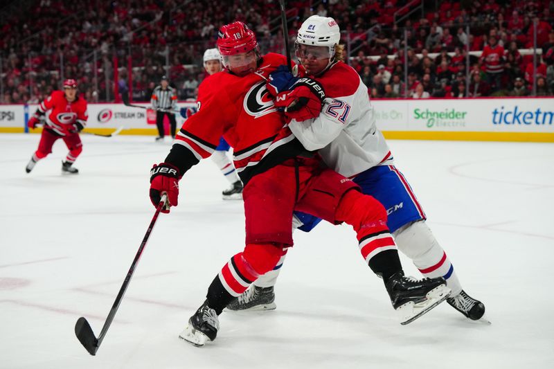 Dec 28, 2023; Raleigh, North Carolina, USA; Carolina Hurricanes center Jack Drury (18) is checked by Montreal Canadiens defenseman Kaiden Guhle (21) during the third period at PNC Arena. Mandatory Credit: James Guillory-USA TODAY Sports