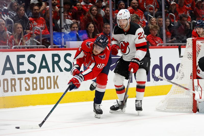 Nov 23, 2024; Washington, District of Columbia, USA; Washington Capitals left wing Pierre-Luc Dubois (80) reaches for the puck in front of New Jersey Devils defenseman Brett Pesce (22) in the first period at Capital One Arena. Mandatory Credit: Geoff Burke-Imagn Images