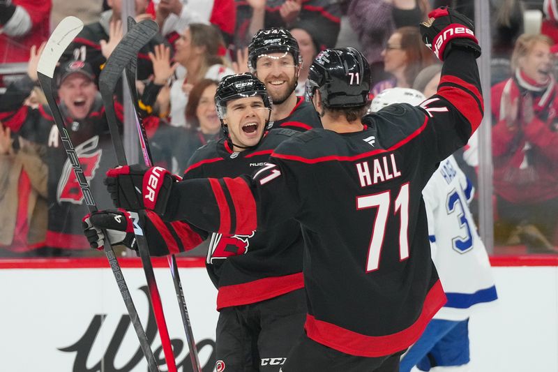 Feb 26, 2026; Raleigh, North Carolina, USA;  Carolina Hurricanes center Logan Stankoven (22) is congratulated by defenseman Jaccob Slavin (74) and left wing Taylor Hall (71) for his goal against the Tampa Bay Lightning during the first period at Lenovo Center. Mandatory Credit: James Guillory-Imagn Images