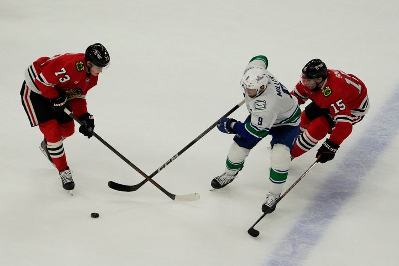 Oct 22, 2024; Chicago, Illinois, USA; Chicago Blackhawks left wing Lukas Reichel (73) center Craig Smith (15) defend Vancouver Canucks center J.T. Miller (9) during the second period at United Center. Mandatory Credit: David Banks-Imagn Images