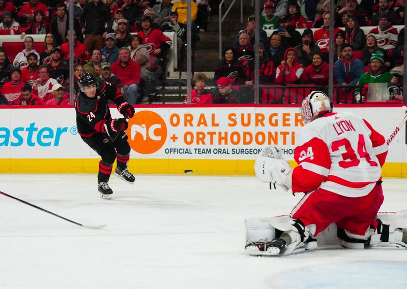 Jan 19, 2024; Raleigh, North Carolina, USA; Carolina Hurricanes center Seth Jarvis (24) takes a shot at Detroit Red Wings goaltender Alex Lyon (34) during the third period at PNC Arena. Mandatory Credit: James Guillory-USA TODAY Sports