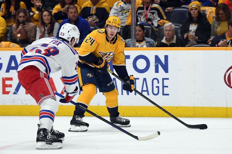 Dec 2, 2023; Nashville, Tennessee, USA; Nashville Predators defenseman Spencer Stastney (24) controls the puck against New York Rangers defenseman Adam Fox (23) during the first period at Bridgestone Arena. Mandatory Credit: Christopher Hanewinckel-USA TODAY Sports