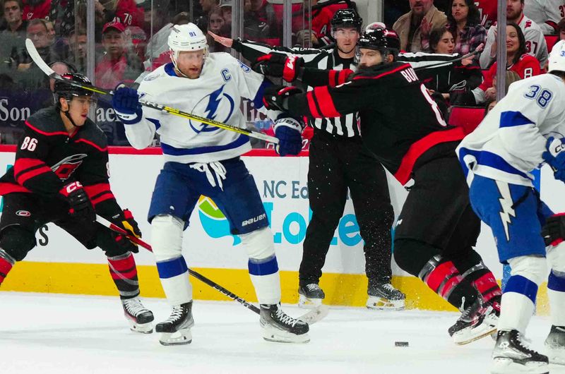 Nov 24, 2023; Raleigh, North Carolina, USA; Carolina Hurricanes defenseman Brent Burns (8) checks Tampa Bay Lightning center Steven Stamkos (91) off the puck during the second period at PNC Arena. Mandatory Credit: James Guillory-USA TODAY Sports