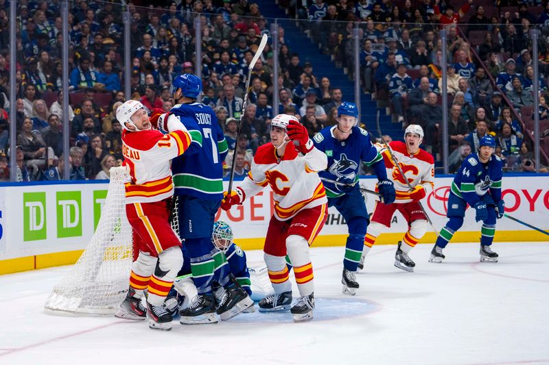 Oct 9, 2024; Vancouver, British Columbia, CAN; Vancouver Canucks goalie Arturs Silovs (31) and defenseman Carson Soucy (7) and defenseman Tyler Myers (57) watch as Calgary Flames forward Martin Pospisil (76) and forward Jonathan Huberdeau (10) celebrate Huberdeau’s goal during the third period at Rogers Arena. Mandatory Credit: Bob Frid-Imagn Images