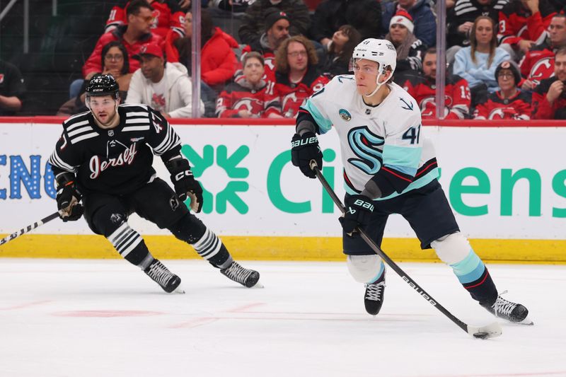 Jan 14, 2026; Newark, New Jersey, USA; Seattle Kraken defenseman Ryker Evans (41) skates with the puck as New Jersey Devils left wing Paul Cotter (47) defends during the second period at Prudential Center. Mandatory Credit: Ed Mulholland-Imagn Images