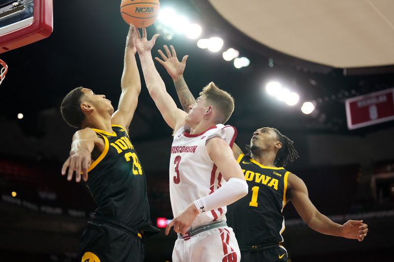 Feb 22, 2023; Madison, Wisconsin, USA; Wisconsin Badgers guard Connor Essegian (3) scores against Iowa Hawkeyes forward Kris Murray (24) and guard Ahron Ulis (1) during the second half at the Kohl Center. Mandatory Credit: Kayla Wolf-USA TODAY Sports