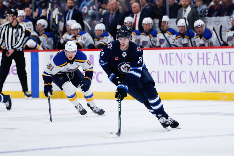 Dec 3, 2024; Winnipeg, Manitoba, CAN;  Winnipeg Jets defenseman Hayden Fleury (24) skates away from St. Louis Blues forward Dylan Holloway (71) during the first period at Canada Life Centre. Mandatory Credit: Terrence Lee-Imagn Images