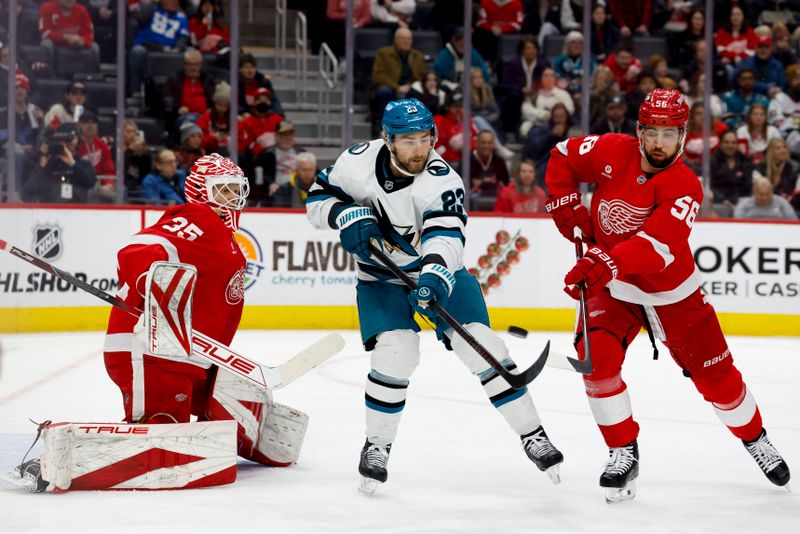Jan 14, 2025; Detroit, Michigan, USA;  San Jose Sharks right wing Barclay Goodrow (23) tries to deflect the puck in front of Detroit Red Wings goaltender Ville Husso (35) and defenseman Erik Gustafsson (56) in the first period at Little Caesars Arena. Mandatory Credit: Rick Osentoski-Imagn Images