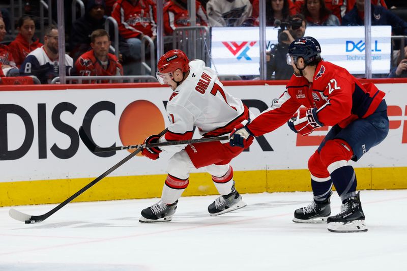 May 6, 2025; Washington, District of Columbia, USA; Carolina Hurricanes defenseman Dmitry Orlov (7) skates with the puck as Washington Capitals right wing Brandon Duhaime (22) chases in the first period in game one of the second round of the 2025 Stanley Cup Playoffs at Capital One Arena. Mandatory Credit: Geoff Burke-Imagn Images
