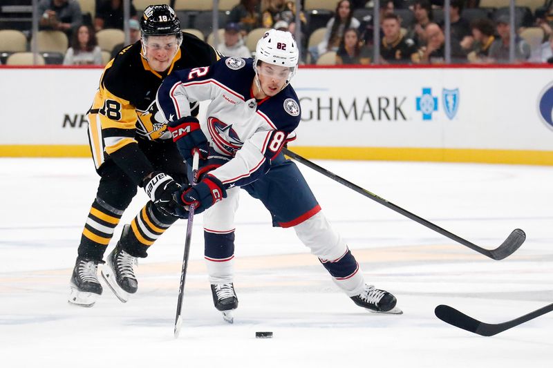 Oct 4, 2024; Pittsburgh, Pennsylvania, USA;  Columbus Blue Jackets left wing Mikael Pyyhtia (82) handles the puck against pressure from Pittsburgh Penguins right wing Jesse Puljujarvi (18) during the second period at PPG Paints Arena. Mandatory Credit: Charles LeClaire-Imagn Images