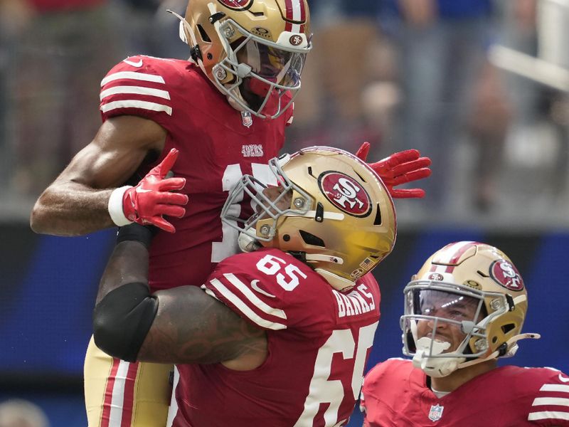 San Francisco 49ers wide receiver Jauan Jennings, top left, is congratulated by guard Aaron Banks (65) and running back Isaac Guerendo (31) after scoring against the Los Angeles Rams during the first half of an NFL football game, Sunday, Sept. 22, 2024, in Inglewood, Calif. (AP Photo/Ashley Landis)