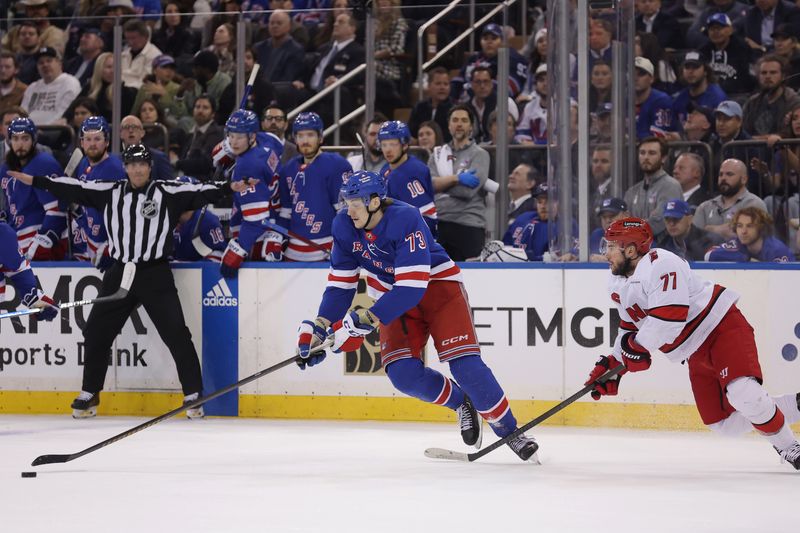 May 13, 2024; New York, New York, USA; New York Rangers center Matt Rempe (73) controls the puck against Carolina Hurricanes defenseman Tony DeAngelo (77) during the first period of game five of the second round of the 2024 Stanley Cup Playoffs at Madison Square Garden. Mandatory Credit: Brad Penner-USA TODAY Sports