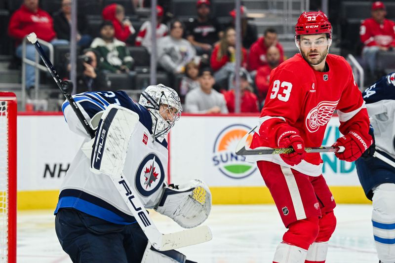 Oct 30, 2024; Detroit, Michigan, USA; Detroit Red Wings right wing Alex DeBrincat (93) attempts to tip the puck in as Winnipeg Jets goaltender Connor Hellebuyck (37) tends the net during the game at Little Caesars Arena. Mandatory Credit: Tim Fuller-Imagn Images