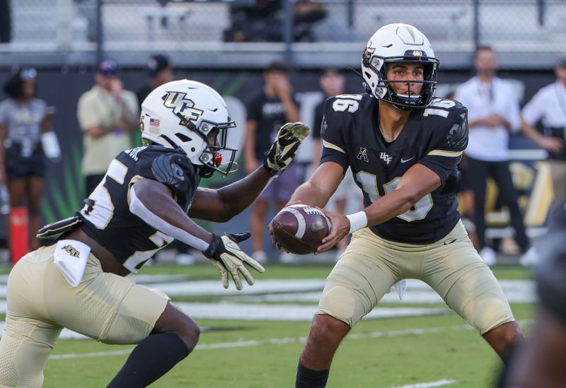 Oct 9, 2021; Orlando, Florida, USA; UCF Knights quarterback Mikey Keene (16) hands off to running back Johnny Richardson (25) during the first quarter against the East Carolina Pirates at Bounce House. Mandatory Credit: Mike Watters-USA TODAY Sports