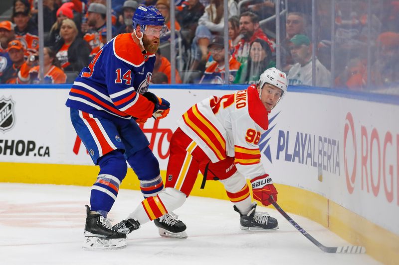 Oct 13, 2024; Edmonton, Alberta, CAN; Calgary Flames forward Andrei Kuzmenko (96) protects the puck from Edmonton Oilers defensemen Mattias Ekholm (14) during the second period at Rogers Place. Mandatory Credit: Perry Nelson-Imagn Images