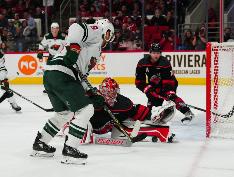 Jan 21, 2024; Raleigh, North Carolina, USA;  Carolina Hurricanes goaltender Antti Raanta (32) stops the scoring attempt by Minnesota Wild defenseman Dakota Mermis (6) during the second period at PNC Arena. Mandatory Credit: James Guillory-USA TODAY Sports