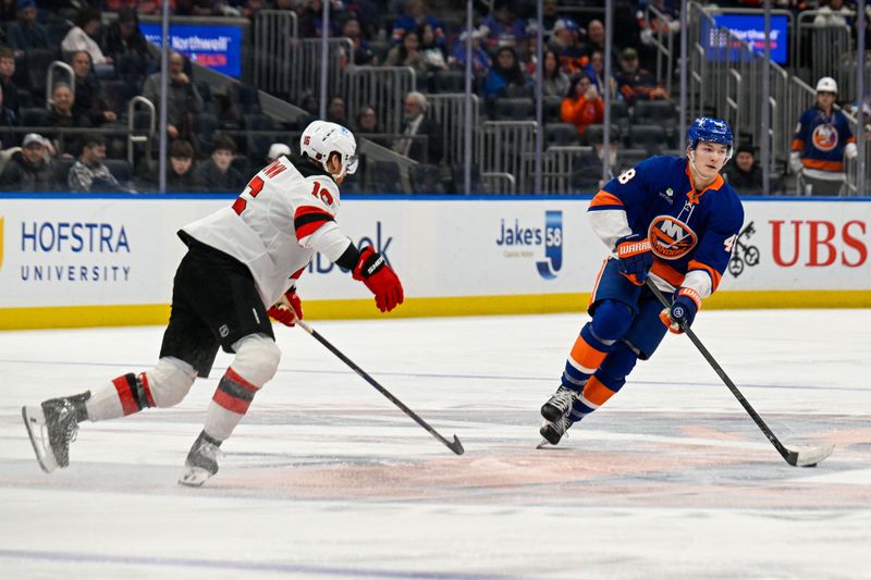 Dec 23, 2025; Elmont, New York, USA;  New York Islanders defenseman Matthew Schaefer (48) skates across center ice defended by New Jersey Devils right wing Connor Brown (16) during the second period at UBS Arena. Mandatory Credit: Dennis Schneidler-Imagn Images