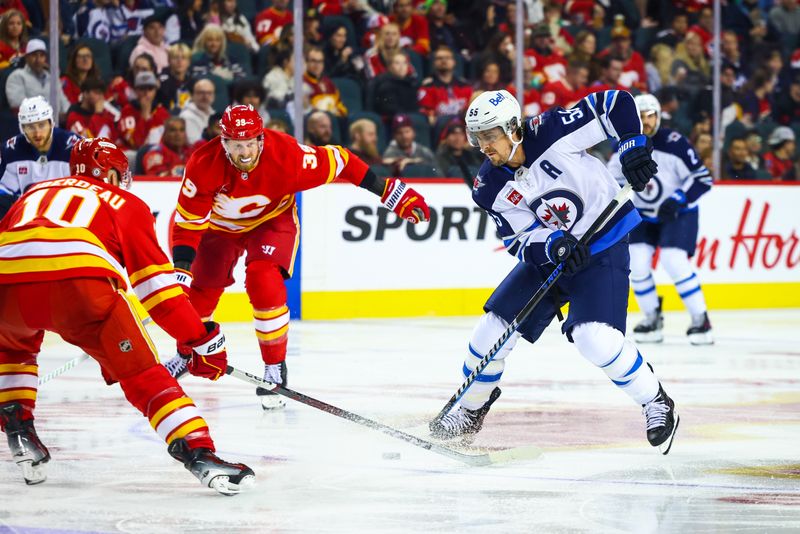 Oct 4, 2024; Calgary, Alberta, CAN; Winnipeg Jets center Mark Scheifele (55) controls the puck against Calgary Flames center Jonathan Huberdeau (10) during the third period at Scotiabank Saddledome. Mandatory Credit: Sergei Belski-Imagn Images