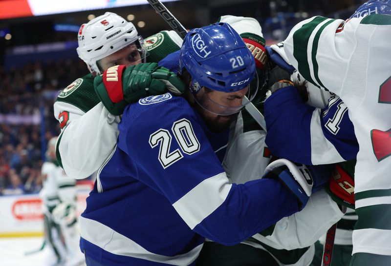 Jan 18, 2024; Tampa, Florida, USA; Minnesota Wild defenseman Jake Middleton (5) and Tampa Bay Lightning left wing Nicholas Paul (20) fight during the first period at Amalie Arena. Mandatory Credit: Kim Klement Neitzel-USA TODAY Sports