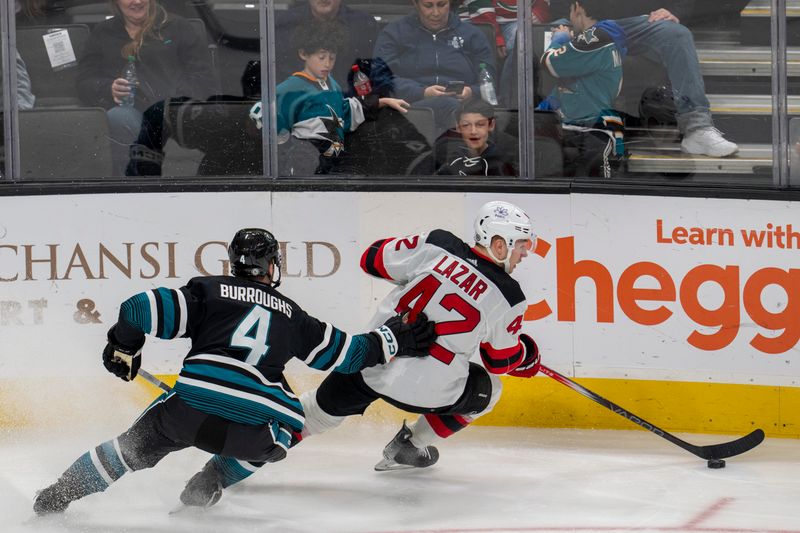 Feb 27, 2024; San Jose, California, USA;  New Jersey Devils center Curtis Lazar (42) controls the puck against San Jose Sharks defenseman Kyle Burroughs (4) during the third period at SAP Center at San Jose. Mandatory Credit: Neville E. Guard-USA TODAY Sports