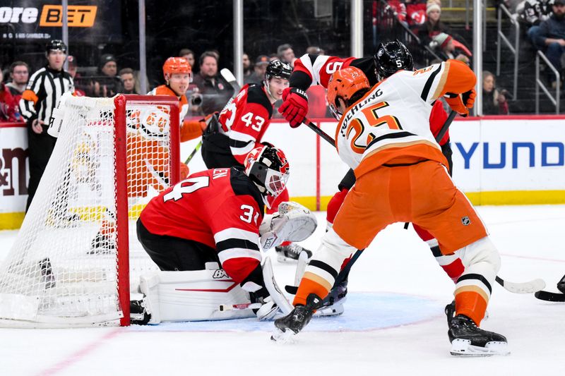 Dec 13, 2025; Newark, New Jersey, USA; New Jersey Devils goaltender Jake Allen (34) makes a save against Anaheim Ducks center Ryan Poehling (25) during the third period at Prudential Center. Mandatory Credit: John Jones-Imagn Images