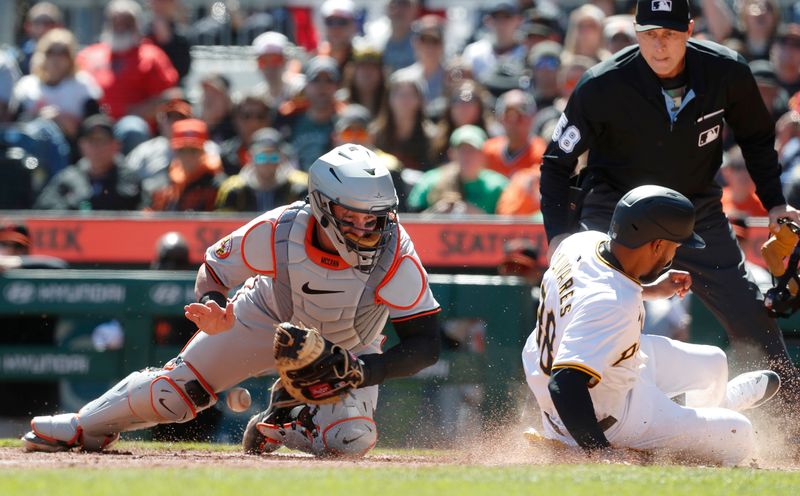 Apr 7, 2024; Pittsburgh, Pennsylvania, USA;  Pittsburgh Pirates designated hitter Edward Olivares (right) slides home to score a run as Baltimore Orioles catcher James McCann (27) misses the catch during the fifth inning at PNC Park. Mandatory Credit: Charles LeClaire-USA TODAY Sports