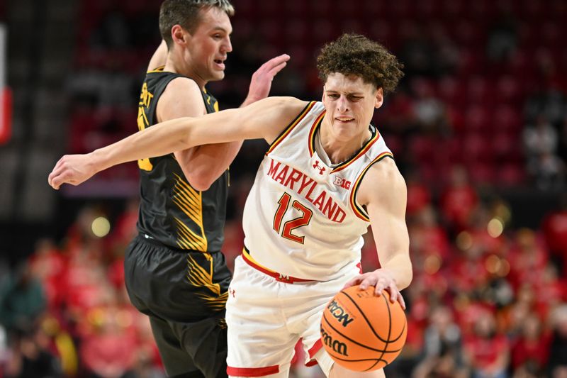 Feb 14, 2024; College Park, Maryland, USA;  Maryland Terrapins forward Jamie Kaiser Jr. (12) dribbles pas Iowa Hawkeyes forward Payton Sandfort (20) during the second half at Xfinity Center. Mandatory Credit: Tommy Gilligan-USA TODAY Sports