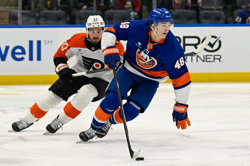 Nov 28, 2025; Elmont, New York, USA; New York Islanders defenseman Matthew Schaefer (48) skates with the puck chased by Philadelphia Flyers left wing Noah Cates (27) during the third period at UBS Arena. Mandatory Credit: Dennis Schneidler-Imagn Images