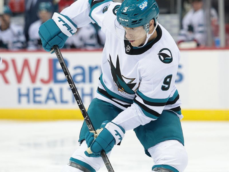 Dec 1, 2023; Newark, New Jersey, USA; San Jose Sharks defenseman Jacob MacDonald (9) deflects the puck for a goal during the second period against the New Jersey Devils at Prudential Center. Mandatory Credit: Vincent Carchietta-USA TODAY Sports