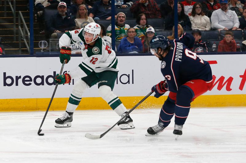 Oct 19, 2024; Columbus, Ohio, USA; Minnesota Wild left wing Matt Boldy (12) controls the puck as Columbus Blue Jackets defenseman Ivan Provorov (9) defends during the third period  at Nationwide Arena. Mandatory Credit: Russell LaBounty-Imagn Images