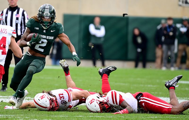 Nov 4, 2023; East Lansing, Michigan, USA; Michigan State Spartans wide receiver Tyrell Henry (2) leaves tacklers Nebraska Cornhuskers defensive back Phalen Sanford (37) and defensive back Tamon Lynum (15) on the turf in the fourth quarter at Spartan Stadium. Mandatory Credit: Dale Young-USA TODAY Sports