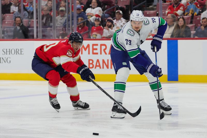 Oct 17, 2024; Sunrise, Florida, USA; Vancouver Canucks defenseman Vincent Desharnais (73) moves the puck past Florida Panthers left wing A.J. Greer (10) during the first period at Amerant Bank Arena. Mandatory Credit: Sam Navarro-Imagn Images