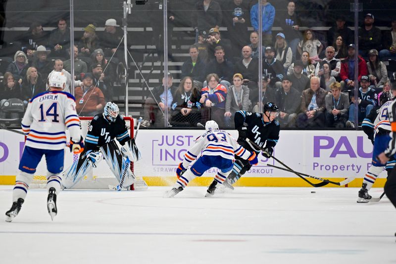 Nov 29, 2024; Salt Lake City, Utah, USA; Utah Hockey Club defenseman Olli Maatta (2) moves the puck past Edmonton Oilers center Connor McDavid (97) during overtime at the Delta Center. Mandatory Credit: Christopher Creveling-Imagn Images