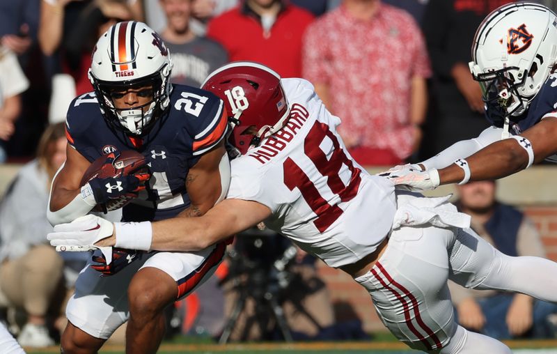 Nov 25, 2023; Auburn, Alabama, USA;  Auburn Tigers running back Brian Battie (21) is tackled by Alabama Crimson Tide defensive back Bray Hubbard (18) during the first quarter at Jordan-Hare Stadium. Mandatory Credit: John Reed-USA TODAY Sports