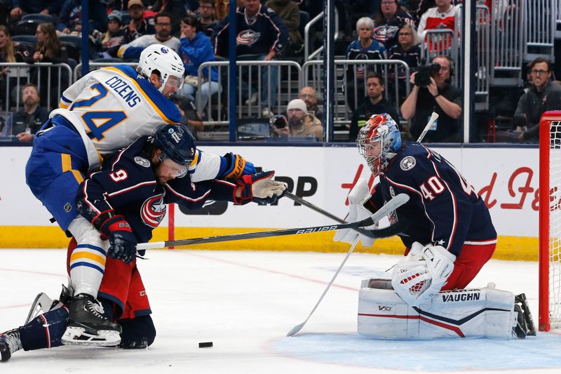 Oct 17, 2024; Columbus, Ohio, USA; Buffalo Sabres center Dylan Cozens (24) reaches over Columbus Blue Jackets defenseman Ivan Provorov (9) for the loose puck during the third period at Nationwide Arena. Mandatory Credit: Russell LaBounty-Imagn Images