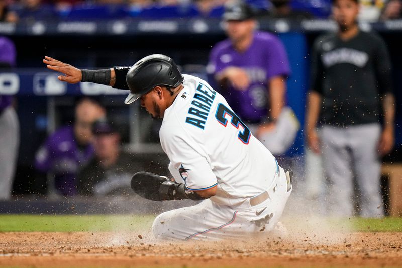 Jul 23, 2023; Miami, Florida, USA; Miami Marlins second baseman Luis Arraez (3) slides into home base against the Colorado Rockies during the sixth inning at loanDepot Park. Mandatory Credit: Rich Storry-USA TODAY Sports