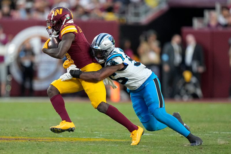 Washington Commanders wide receiver Olamide Zaccheaus is tackled by Carolina Panthers linebacker Trevin Wallace (56) after catching a pass during the second half of an NFL football game, Sunday, Oct. 20, 2024, in Landover, Md. (AP Photo/Stephanie Scarbrough)