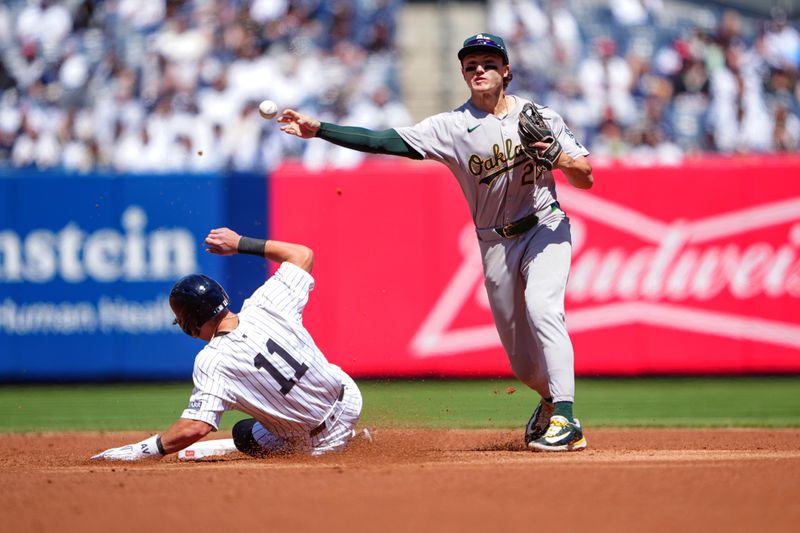 Apr 22, 2024; Bronx, New York, USA; Oakland Athletics second baseman Zack Gelof (20) turns a double play against New York Yankees shortstop Anthony Volpe (11) during the first inning at Yankee Stadium. Mandatory Credit: Gregory Fisher-USA TODAY Sports